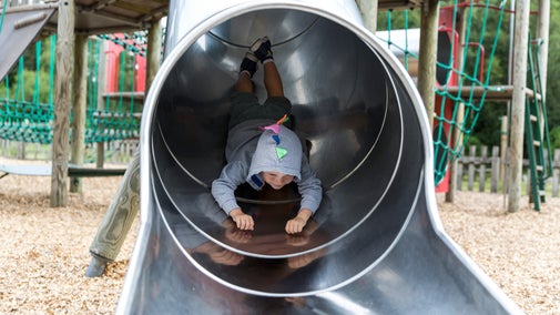 A child sliding down one of the tunnels head first at Cragside's adventure play area.